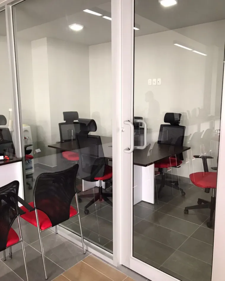 Oficinas con mamparas de vidrio y sillas rojas en AutoExcel San Pedro Sula